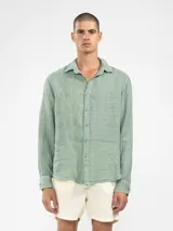 Camisa de manga larga confeccionada 100% en lino, color verde claro, con calce recto y relajado. Presenta frente abotonado con botones de coco con logo y el patch característico de Polonio.