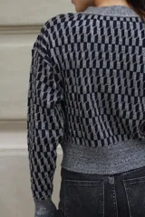 Cárdigan de tejido de punto con diseño geométrico en blanco, negro y beige. Corte recto, con botones al frente y lurex.