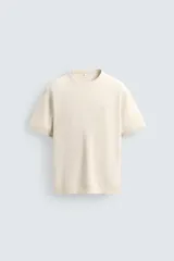 Camiseta de punto de algodón con textura perlada, corte regular, cuello redondo y manga corta con terminaciones en rib.