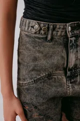 Short de jean gris oscuro con efecto desgastado y roturas, tiro alto y ruedo desflecado.