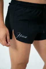 Short deportivo negro con cintura elástica ajustable con cordón, corte holgado y aberturas laterales.