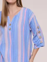 Blusa Erika de algodón con estampado de rayas en tonos azules, rosados y amarillos. Presenta cuello redondo con escote en V y botones frontales, mangas cortas decoradas con una fila de botones en los laterales y dobladillo asimétrico.