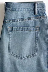 Jean de cinco bolsillos en denim de algodón rígido, de diseño curvo con volumen y corte holgado de cadera a muslo, algo más ceñidas en el bajo. Cintura clásica con cierre y botón.