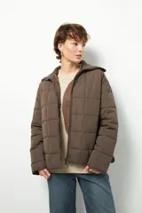Campera acolchada de color marrón, con diseño capitoneado, cierre frontal completo y cuello alto de tejido acanalado.