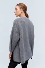 Sweater gris de punto grueso con cuello redondo y mangas largas. Tiene corte holgado y cierre lateral con cremallera.