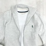 Campera gris claro melange con cierre frontal, cuello alto y bolsillos laterales.