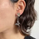 Par de aros colgantes plateados con forma de mariposa y base cuadrada.