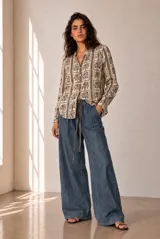 Camisa de manga larga color beige con estampado geométrico y floral en tonos marrones y naranjas, escote en V y botonadura frontal.