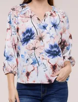 Blusa de gasa liviana blanca con estampado floral en tonos azules y rosados, escote en V, mangas 3/4 abullonadas con puños elásticos y corte fluido.