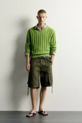 Sweater de punto canalé en hilatura de algodón, color verde, con cuello en V y manga larga.