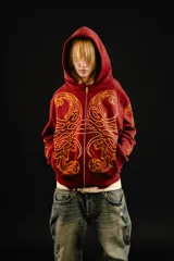 Hoodie con cierre frontal, color bordó, con estampado serigráfico en color dorado que recorre el frente y las mangas con un diseño inspirado en hojas de acanto. Cuenta con bolsillos laterales y cierre metálico.