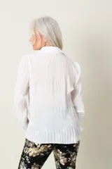 Camisa blanca plisada de manga larga con cuello clásico.