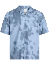 Camisa de manga corta Calvin Klein con cuello cubano y cierre frontal de botones. Presenta un estampado tie-dye sobre una base de tejido cuadriculado y cuenta con el logo de la marca bordado en el pecho.
