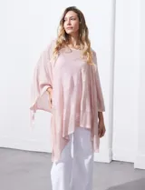 Poncho tejido calado color rosa con lurex, de terminación asimétrica.