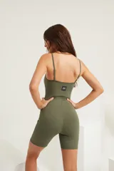 Catsuit corto verde oliva de alta compresión con breteles regulables y etiqueta ZN en la espalda.