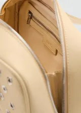 Bolso tipo bowling de color beige, adornado con múltiples ojales metálicos plateados en la parte frontal. Cuenta con doble asa de mano superior y cierre con cremallera.