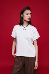 Remera blanca de manga corta con cuello redondo, hombros caídos y silueta amplia.