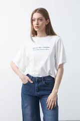 Remera blanca de manga corta con bordado frontal en azul que dice "dolce far niente the sweetness of doing nothing". Tiene un calce relajado.
