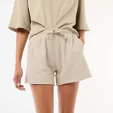 Short de felpa beige de corte holgado, con cintura elástica ajustable mediante cordón y bolsillos laterales.