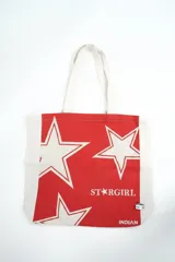 Bolso tipo tote bag de color crudo con estampado de flores celestes y centros azul oscuro. Cuenta con doble asa de hombro en tono crudo y etiqueta con la marca en el frente.