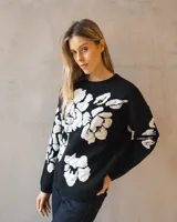 Sweater de tejido de punto en color negro con diseño floral en contraste blanco, de corte holgado y cuello redondo.