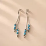 Caravanas colgantes de plata con doble cadena y cuentas cilíndricas de resina color turquesa y cuentas plateadas.