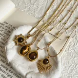 Set de tres collares dorados con dijes de piedra ojo de tigre con diferentes diseños: sol con strass, lágrima y abanico.
