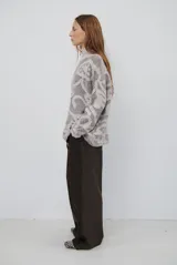 Buzo de tejido de punto con cierre frontal, cuello alto y diseño estampado en tonos beige y marrón.