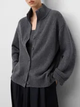 Cárdigan de punto en color gris, confeccionado en lana merino. Presenta cuello perkins, cierre frontal con botones, mangas largas con hombro caído y puños y ruedo acanalados.
