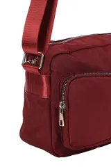 Bandolera de nylon color bordó, con correa ajustable, compartimento principal con cierre y dos bolsillos frontales con cierre.