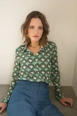 Camisa de manga larga con cuello camisero y cierre frontal de botones, confeccionada en tela estampada con un patrón geométrico de abanicos en tonos verdes y beige.