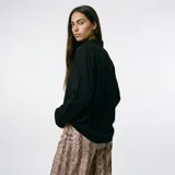 Blusa de corte clásico y diseño holgado, con cuello camisero, cierre frontal de botones y mangas largas con puños abotonados.