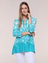 Blusa turquesa con estampado paisley y geométrico blanco, de corte holgado y evasé, con mangas tres cuartos y escote redondo con detalle de abertura tipo keyhole y galón tejido.