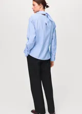 Blusa de manga larga con diseño de rayas verticales en tonos azul y blanco. Presenta un cuello redondo con un pañuelo integrado que cae sobre el pecho y puños abotonados.