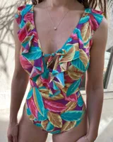 Malla enteriza con estampado de hojas en tonos turquesa, rosa, marrón y violeta. Tiene escote en V con volados y lazo ajustable en el centro.