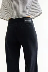 Pantalón de jean negro de tiro bajo con corte recto y ajuste mediante cordones en la botamanga, permitiendo un estilo tipo balloon.