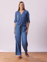 Blusa celeste de tencel, marca Alex & Parker. Cuello a la base, escote en V y abertura central con botones. Delantera con bolsillos. Largo de manga regulable con presilla y botón. Terminación de ruedo con nudo.