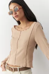 Remera blanca de manga larga con cuello redondo y costuras a la vista.