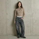 Polera de manga larga en color beige, confeccionada en tejido de punto acanalado. Presenta un cuello alto con un detalle de lazo lateral que le otorga un toque distintivo y elegante.