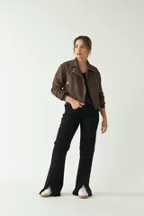 Pantalón negro de tiro medio, corte ajustado en la cadera y piernas que se ensanchan. Presenta cortes en el bajo de cada pierna.