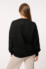 Buzo tejido color gris claro, de corte oversize y cuello redondo.