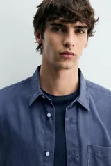 Camisa de corte regular fit en color azul, confeccionada en mezcla de lyocell y algodón, con cuello camisero, manga larga con puños abotonados, cierre frontal con botones y un bolsillo aplicado en el pecho.