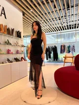 Vestido midi negro con escote palabra de honor, cuerpo entallado y falda con sobrecapa de tul transparente que aporta volumen y movimiento.