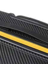 Valija rígida color negro con textura de fibra de carbono y detalles en amarillo. Cuenta con cuatro ruedas dobles, carro extensible y cierre principal con detalles en contraste.