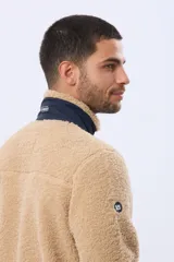 Campera de corderito con interior de polar, cuello alto y cierre frontal. Presenta un bolsillo vertical con cierre en el pecho, bolsillos laterales y detalles de ribete en contraste.