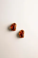 Aros de diseño orgánico con centro de resina en tono ámbar y borde metálico dorado.