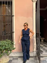 Musculosa de jean azul oscuro, sin mangas, con diseño fruncido tipo corset en el torso y terminación con volados en la cintura.