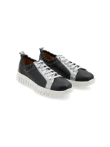 Sneaker de cuero negro con detalles plateados, suela anatómica blanca y elástico en el tobillo.