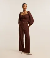 Pantalón sastrero marrón de corte recto y cintura alta, con trabillas en la cintura, bolsillos delanteros y traseros simulados, cierre tradicional y botones metalizados.