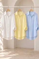 Camisa de algodón celeste, de corte holgado, mangas largas con presillas para arremangar y cierre frontal con botones.